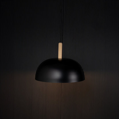 Black dome pendant ceiling light with wooden top illuminated on back background for dining room cafe and modern home interior lighting.