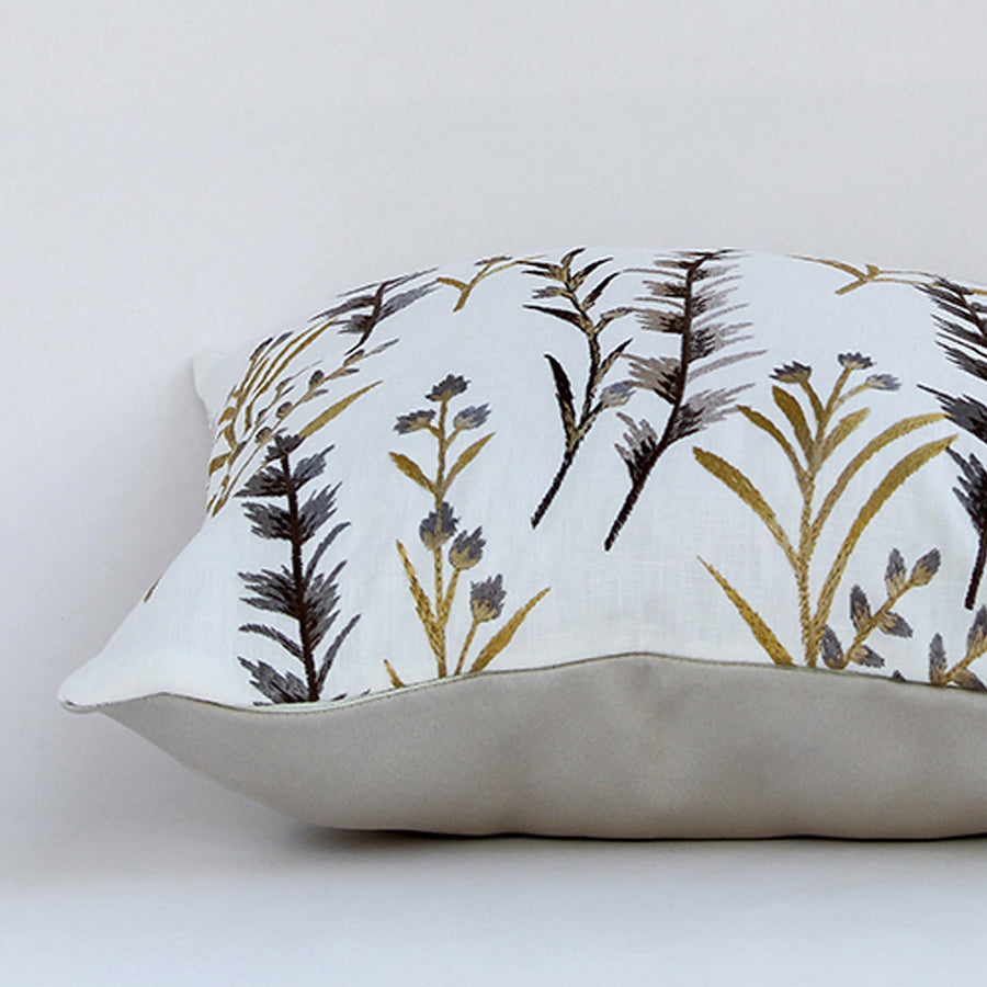 Closeup view of botanical embroidered cushion showing fine cotton texture and detailed yellow and grey stitched motifs ideal for warm modern decor styling.