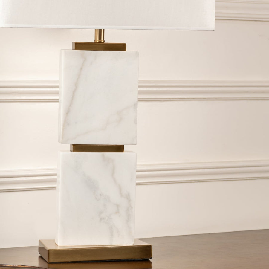 White shade marble block table lamp on wooden sideboard with light off and white panel wall background for modern luxury décor.