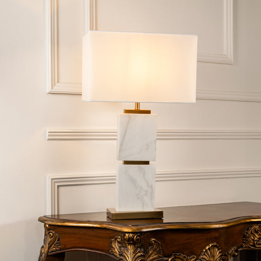 Teal glass table lamp with fabric shade displayed on a wooden console table creating elegant ambient lighting indoors.