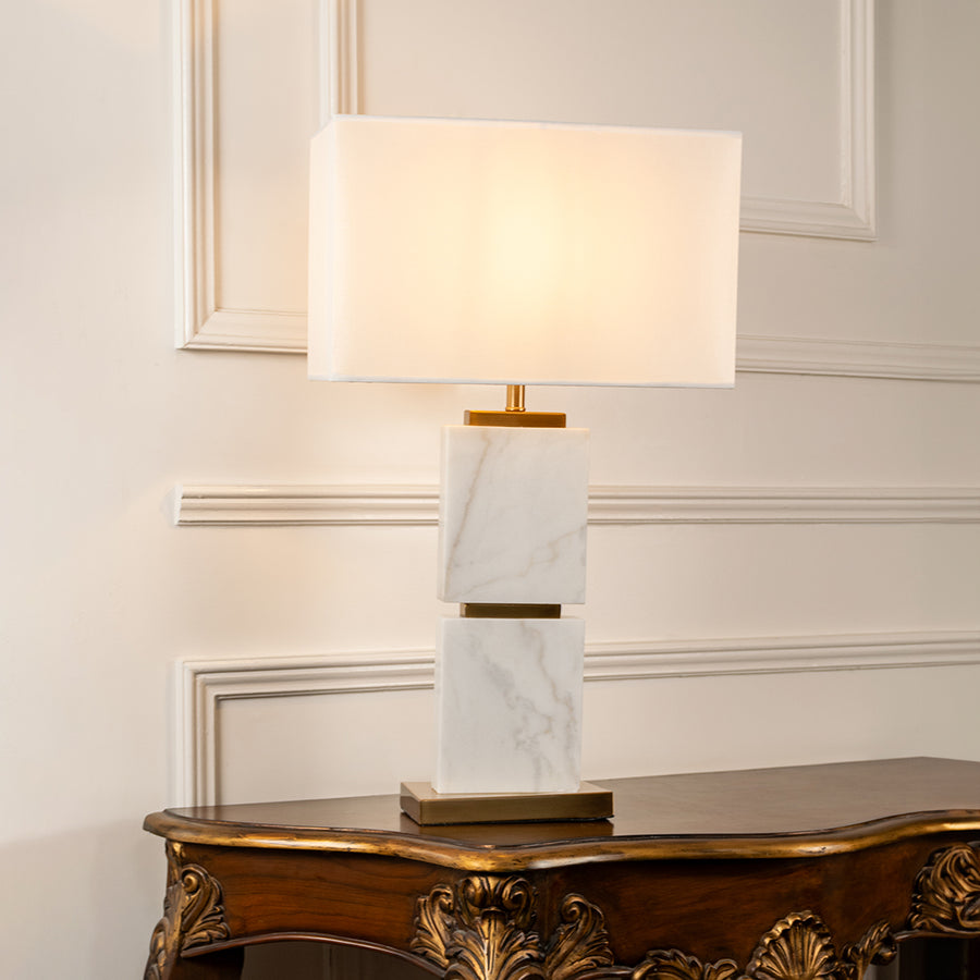 Teal glass table lamp with fabric shade displayed on a wooden console table creating elegant ambient lighting indoors.