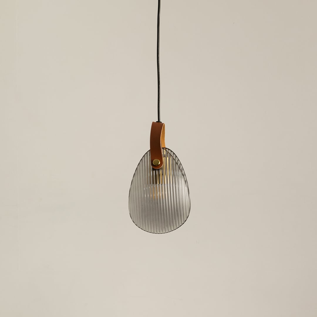 Ribbed glass pendant light with leather strap displayed off on a clean white background for minimalist lighting style.