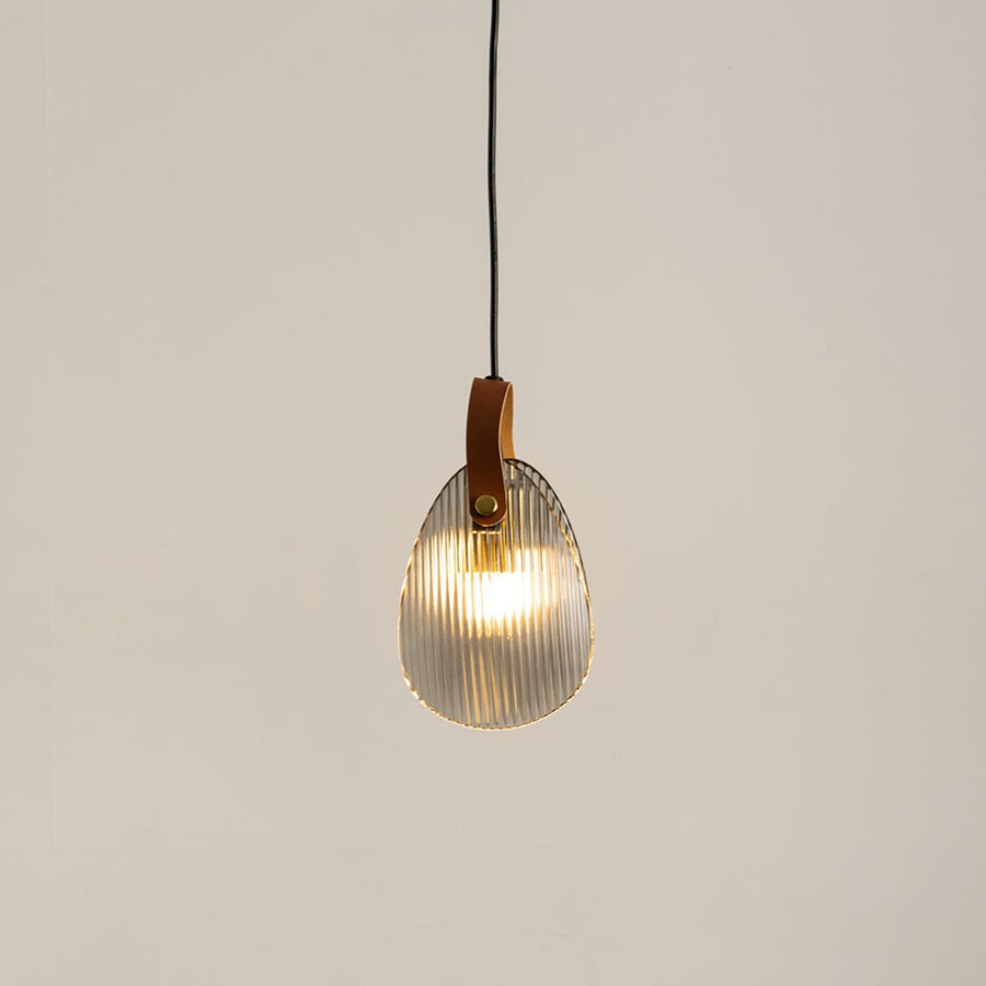 Ribbed glass pendant light with leather strap glowing on a white background for modern hanging lighting decor.