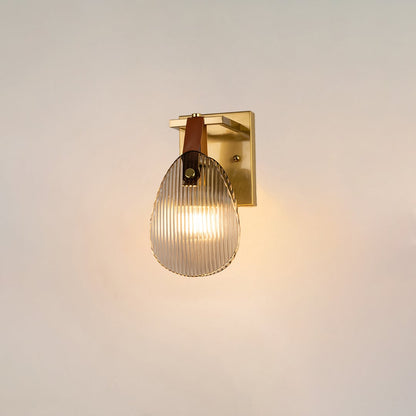 Gold wall light with ribbed glass shade and leather strap glowing on a white background for modern home lighting.