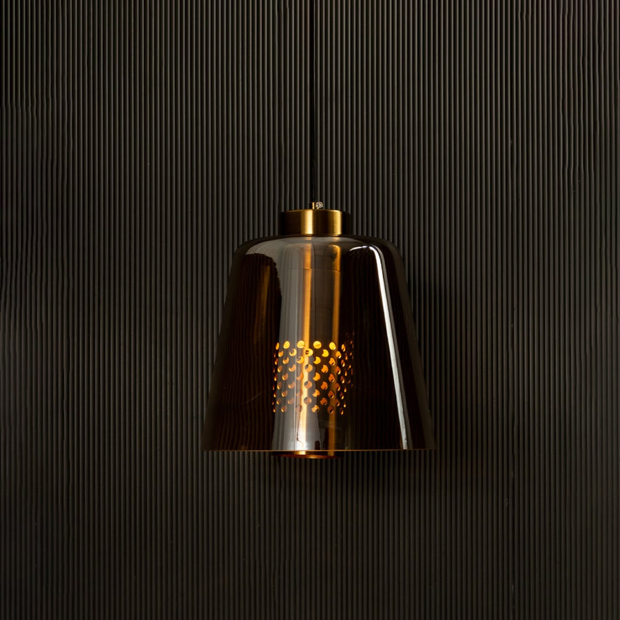Gold metallic pendant light illuminated on black background creating a rich warm glow and bold reflective look for modern interior lighting.
