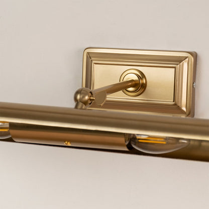 Closeup of gold metal picture light showing smooth finish adjustable arm and warm directional illumination.