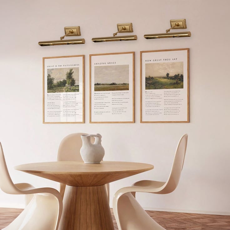 Gold metal picture lights styled together on a modern wall creating warm balanced illumination for home interiors.