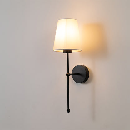 Closeup wall light in black metal finish with fabric shade for bedroom or living room ambient lighting decor white background.