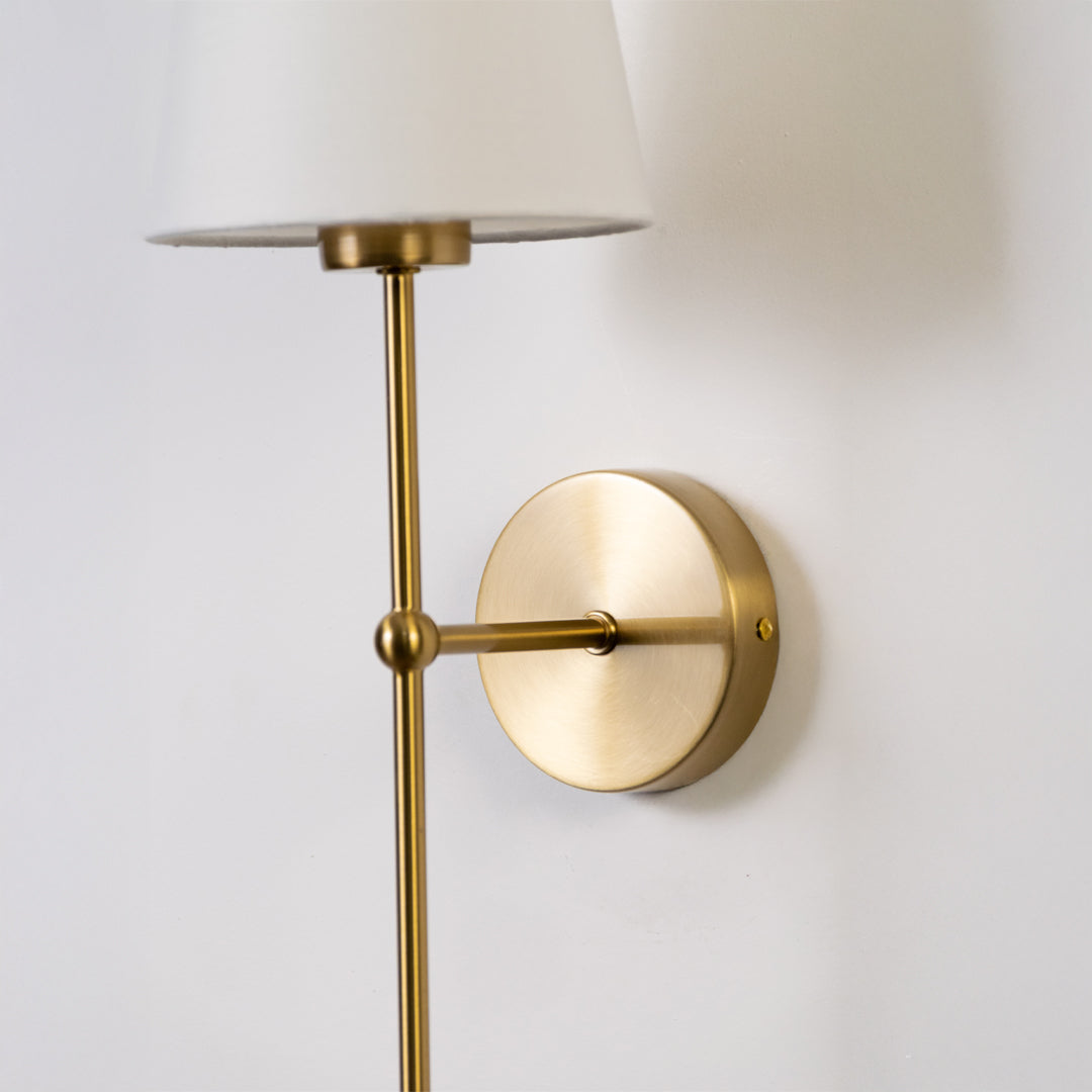 Contemporary wall light in gold metal finish with fabric shade for bedroom or living decor lighting white background.