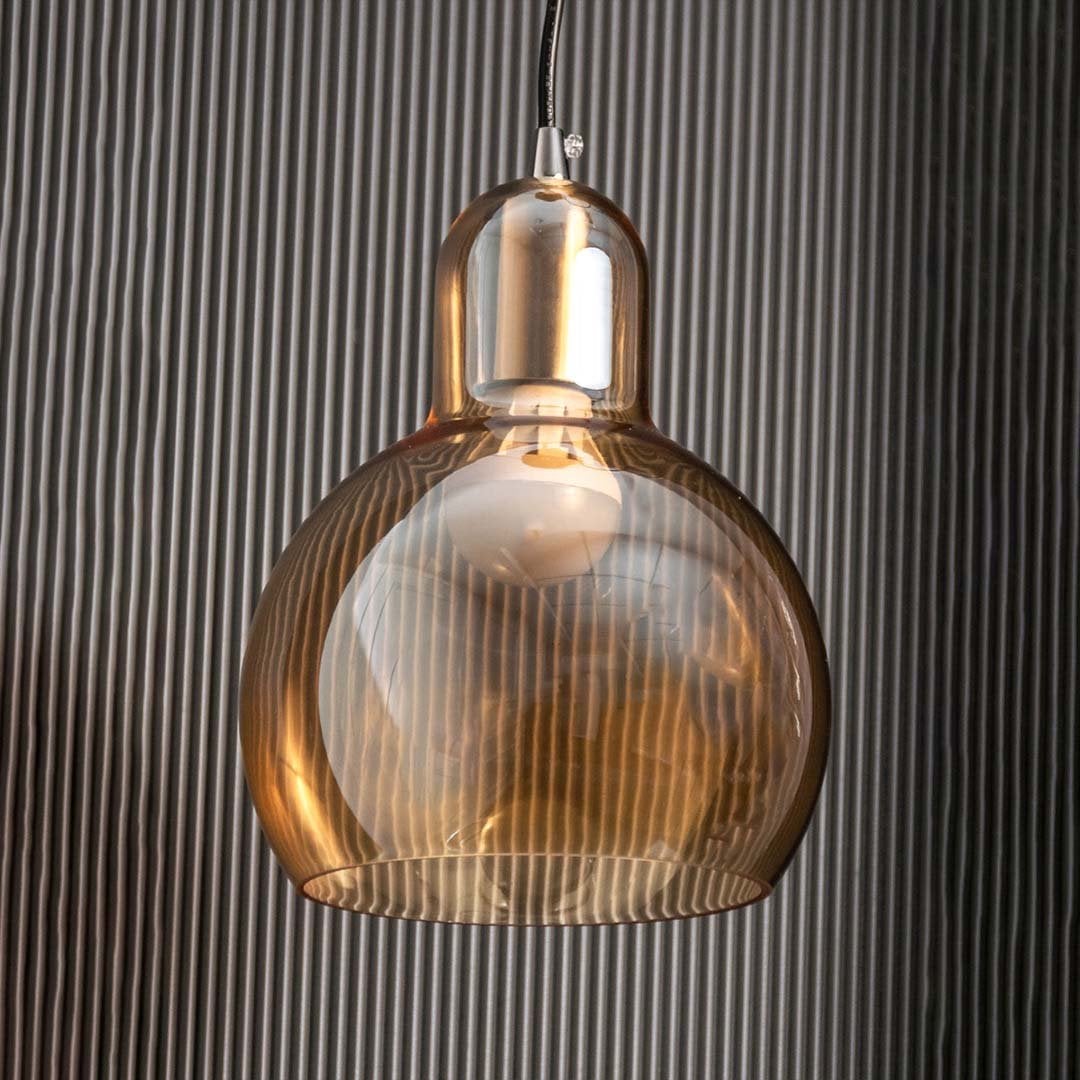 Pendant light with amber glass shown against a black textured background with the light off highlighting the natural transparency and smooth finish.