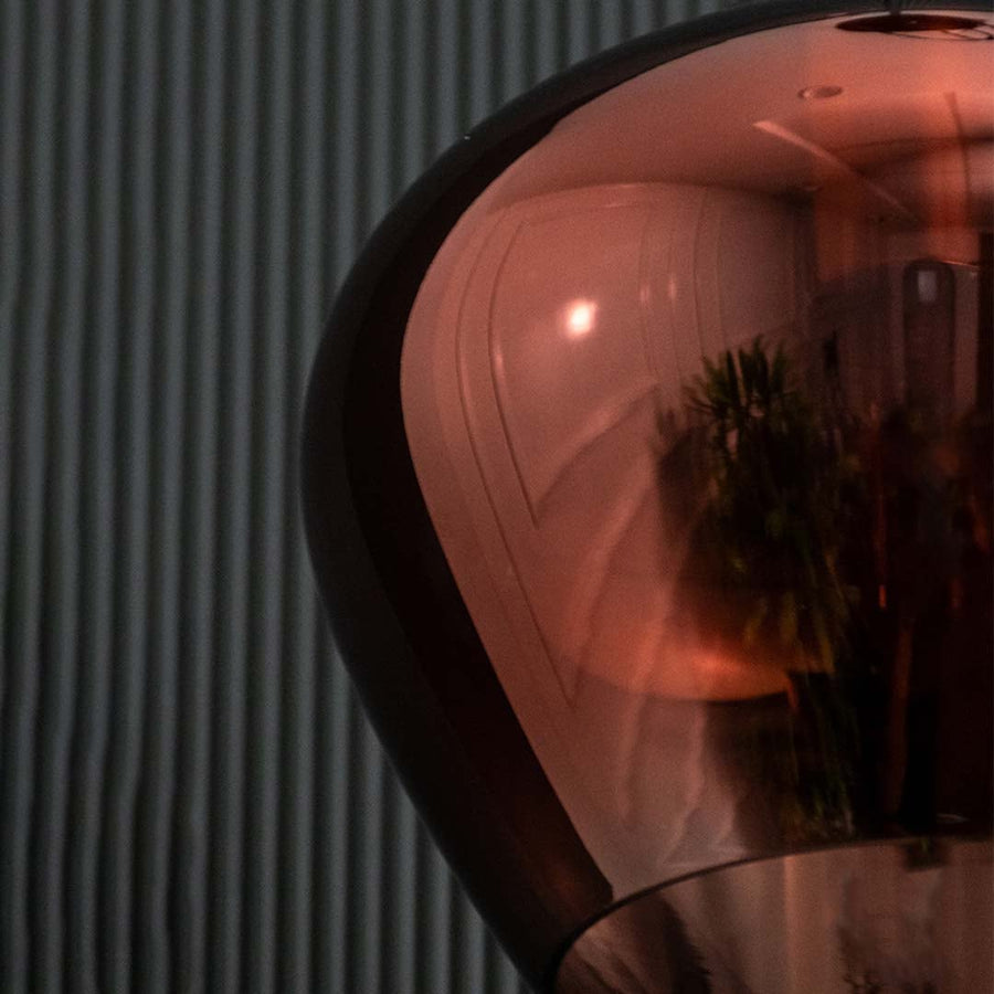 A closeup view of the amber pendant light focusing on the top metal fitting and smooth transition into the curved glass shade showing refined craftsmanship.