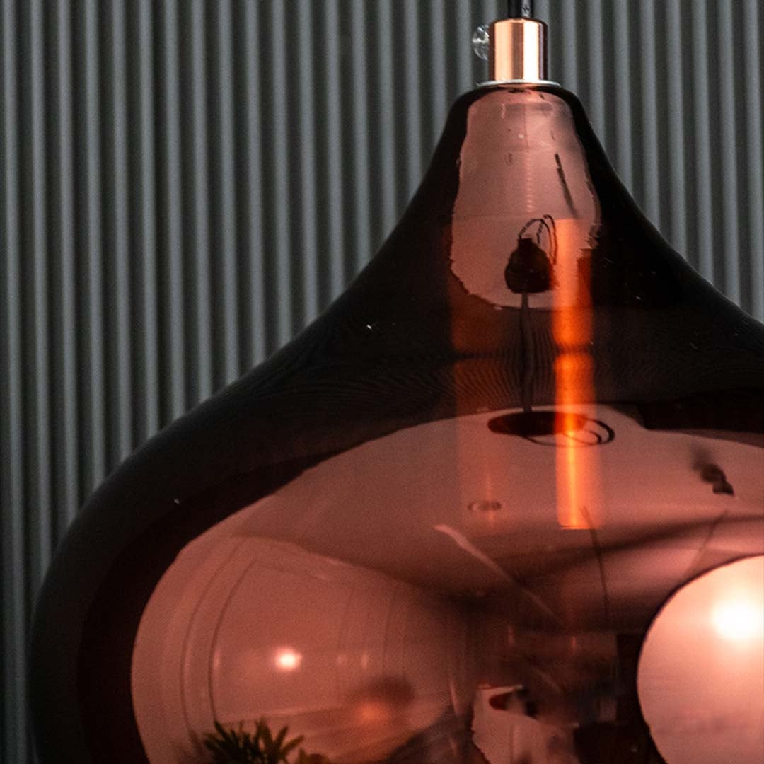 A detailed closeup of an amber glass pendant light showing the rippled reflective surface and inner bulb structure with tinted glass detail.