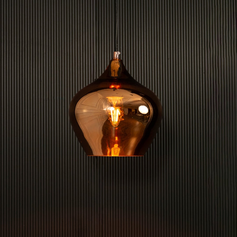 Gold reflective pendant light glowing on black background creating dramatic warm lighting and a bold modern metallic decorative look.