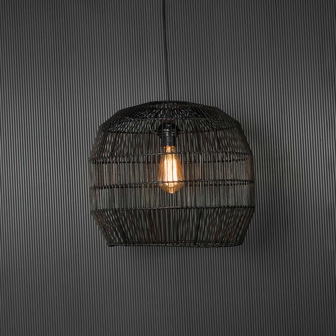 Stylish black rattan pendant light glowing on dark background highlighting intricate weaving and soft ambient illumination.