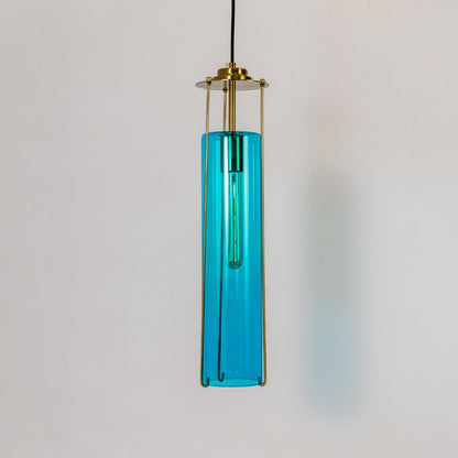Blue glass pendant light turned off against a crisp white background highlighting its rich color clean lines and modern brass frame design.