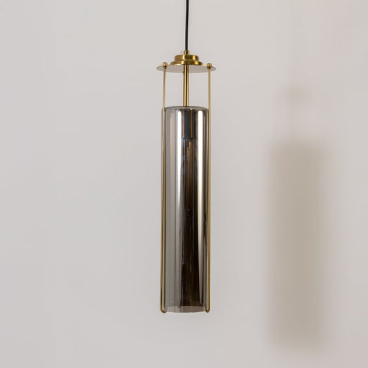 Smoked glass pendant light turned off on a white background showing its tall cylinder shade and refined brass structure in detail.
