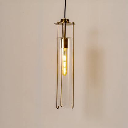 Elegant clear glass pendant light glowing warmly against a clean white background highlighting its slim cylindrical shape and brass accents.