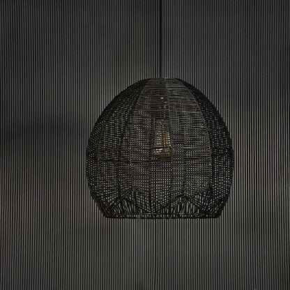 Stylish black rattan pendant light against black background highlighting fine weaving structure and artisanal handmade texture.