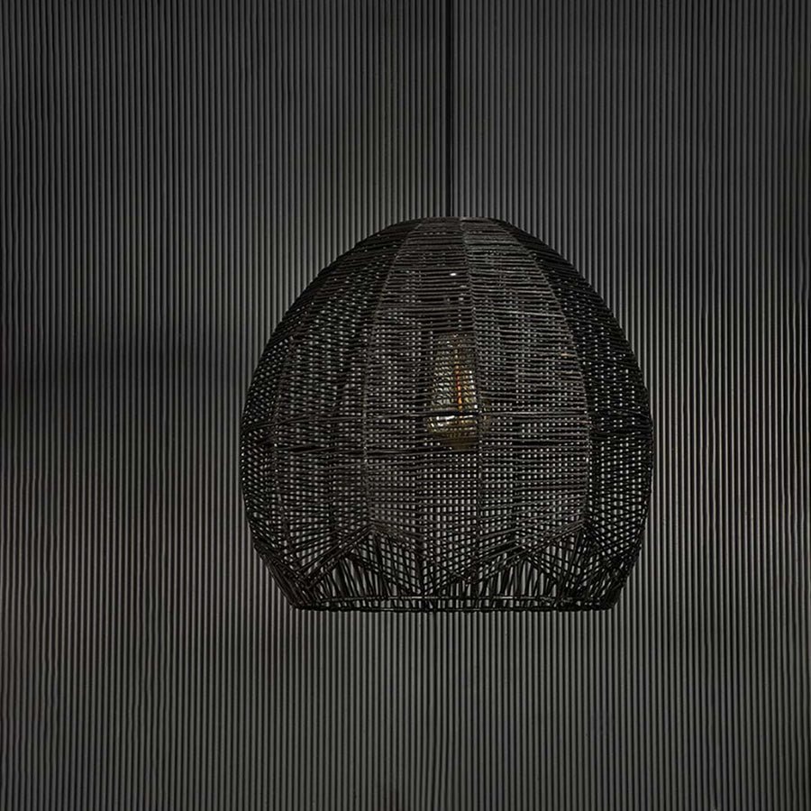 Stylish black rattan pendant light against black background highlighting fine weaving structure and artisanal handmade texture.
