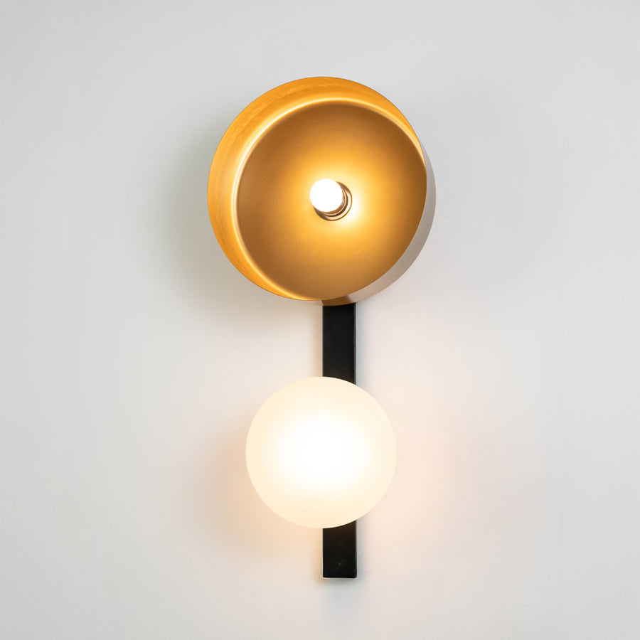 Contemporary wall light in gold metal finish with globe and disc design for bedroom or living decor lighting white background.