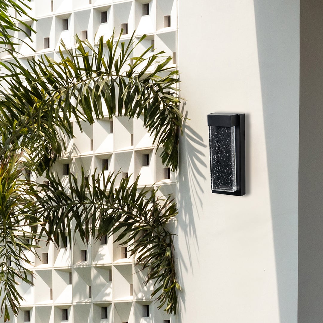Slim outdoor wall light installed on exterior wall beside plants adding subtle architectural lighting to modern home exteriors.