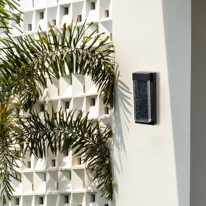 Slim outdoor wall light installed on exterior wall beside plants adding subtle architectural lighting to modern home exteriors.