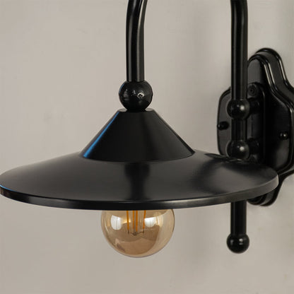 Close detailed view of the black wall light showing the curved metal frame wide shade and warm glowing bulb for a sleek contemporary look.