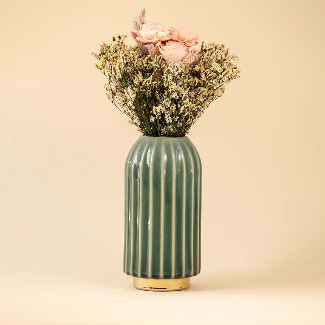 Tall green ceramic vase with gold base and soft pink flowers placed against white background for an elegant modern home decor look.