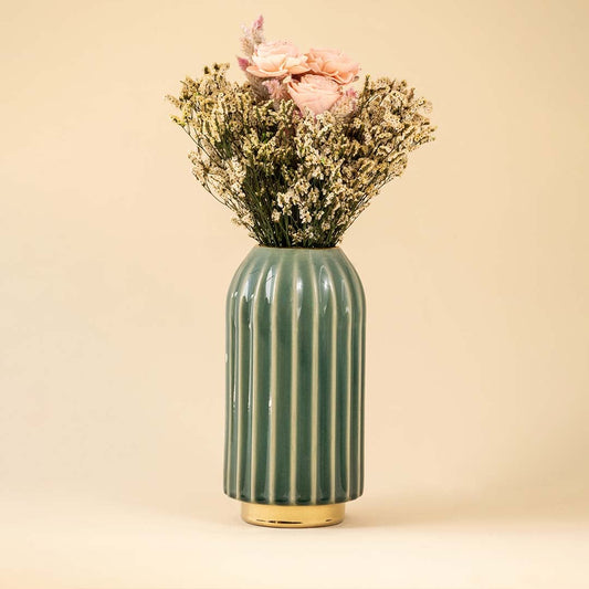 Tall green ceramic vase with gold base and soft pink flowers placed against white background for an elegant modern home decor look.