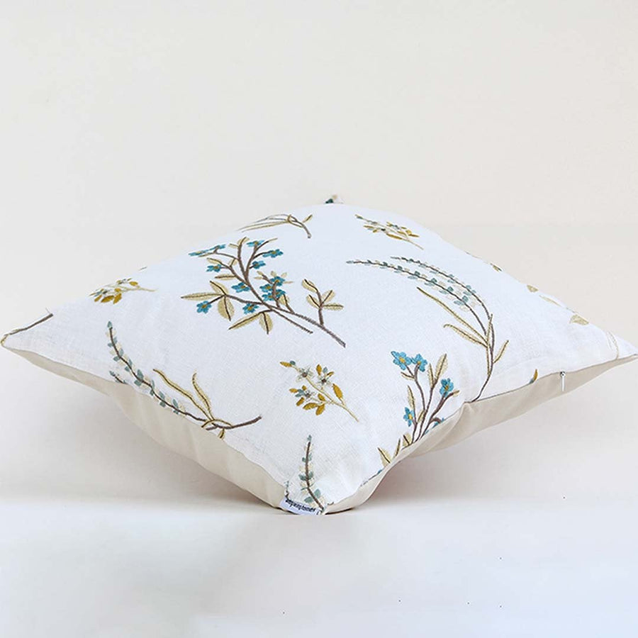 A white background image displaying a botanical embroidered cushion with delicate leaves and floral stitching highlighting the design clearly against a plain backdrop.