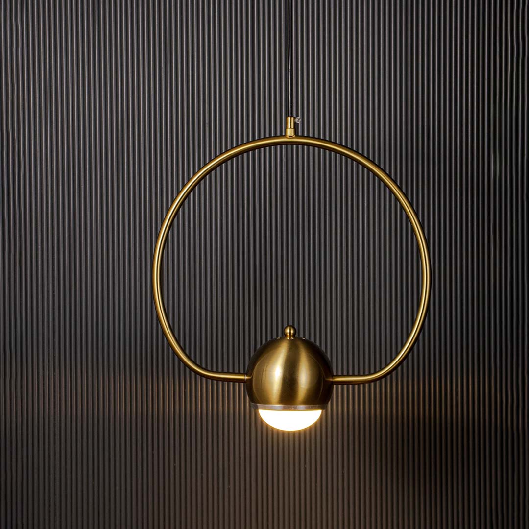 Brass gold wall lamp with frosted glass globe glowing softly against dark wall backdrop creating a warm luxury ambience.