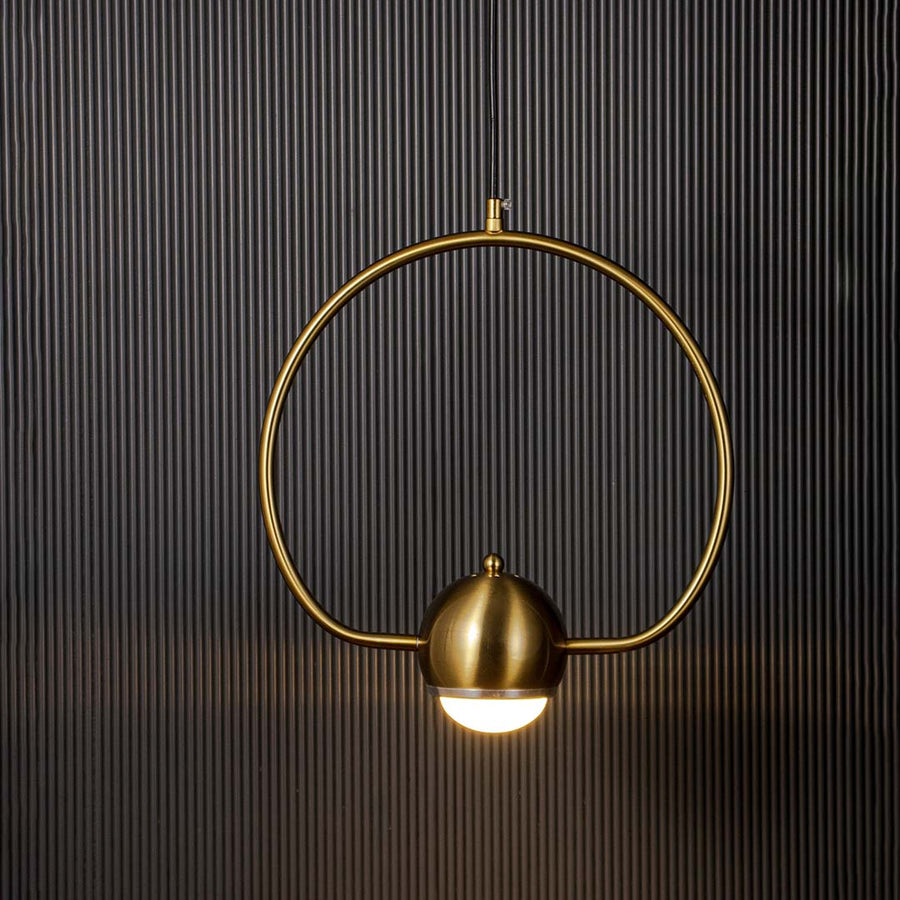 Brass gold wall lamp with frosted glass globe glowing softly against dark wall backdrop creating a warm luxury ambience.