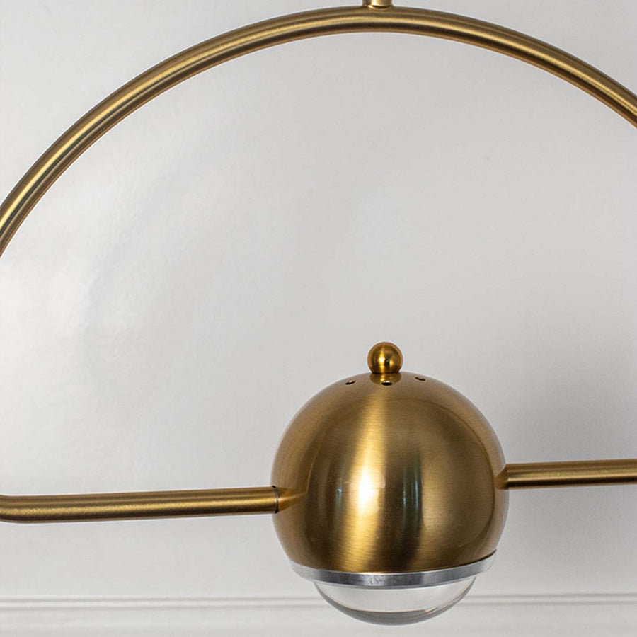 Closeup of golden pendant light with dome glass diffuser sleek arch frame design elegant ceiling lamp for home interior lighting.