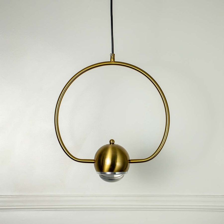 Contemporary wall lamp in brass gold finish with circular metal frame and frosted globe shade shown turned off elegantly.
