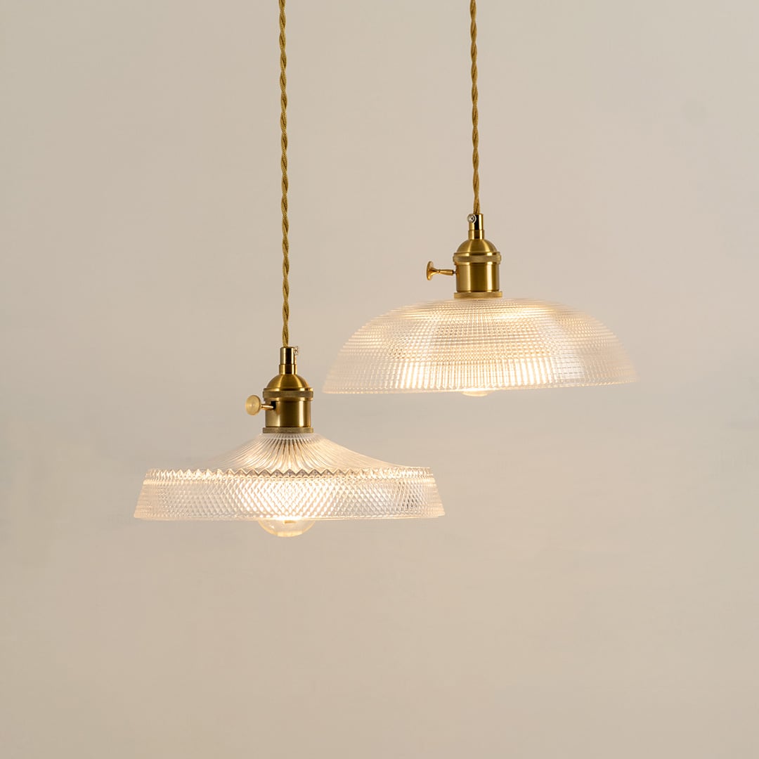 Pair of clear patterned glass pendant lights with gold fittings adding timeless elegance to modern spaces.