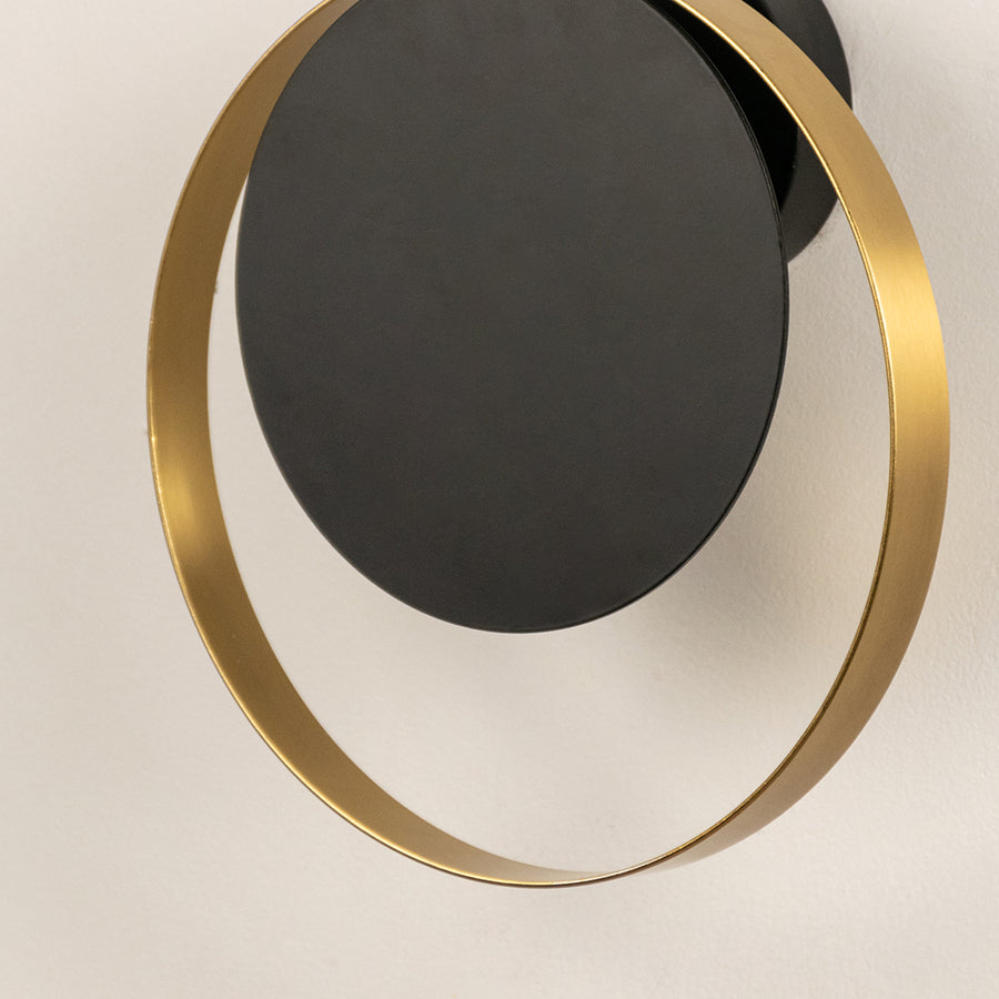 Contemporary black and brass circular wall light with sleek metallic ring for luxury interior decor.
