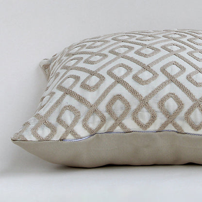 Closeup of the cushion highlighting the detailed beige geometric embroidery and rich textured fabric.