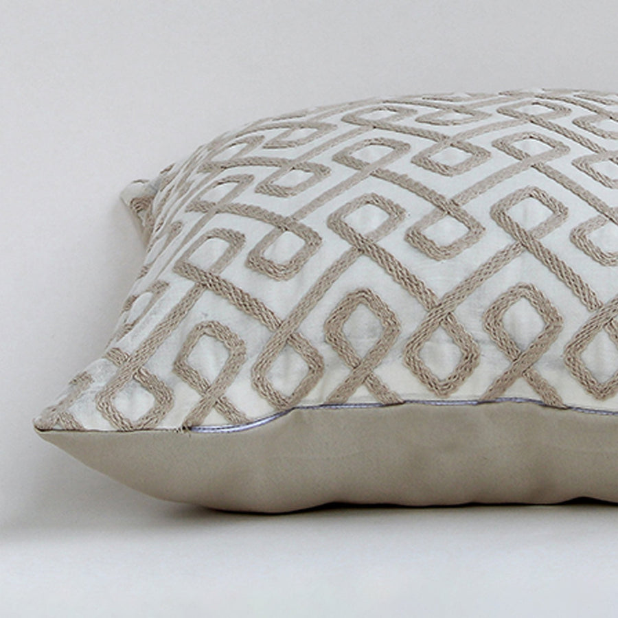 Closeup of the cushion highlighting the detailed beige geometric embroidery and rich textured fabric.