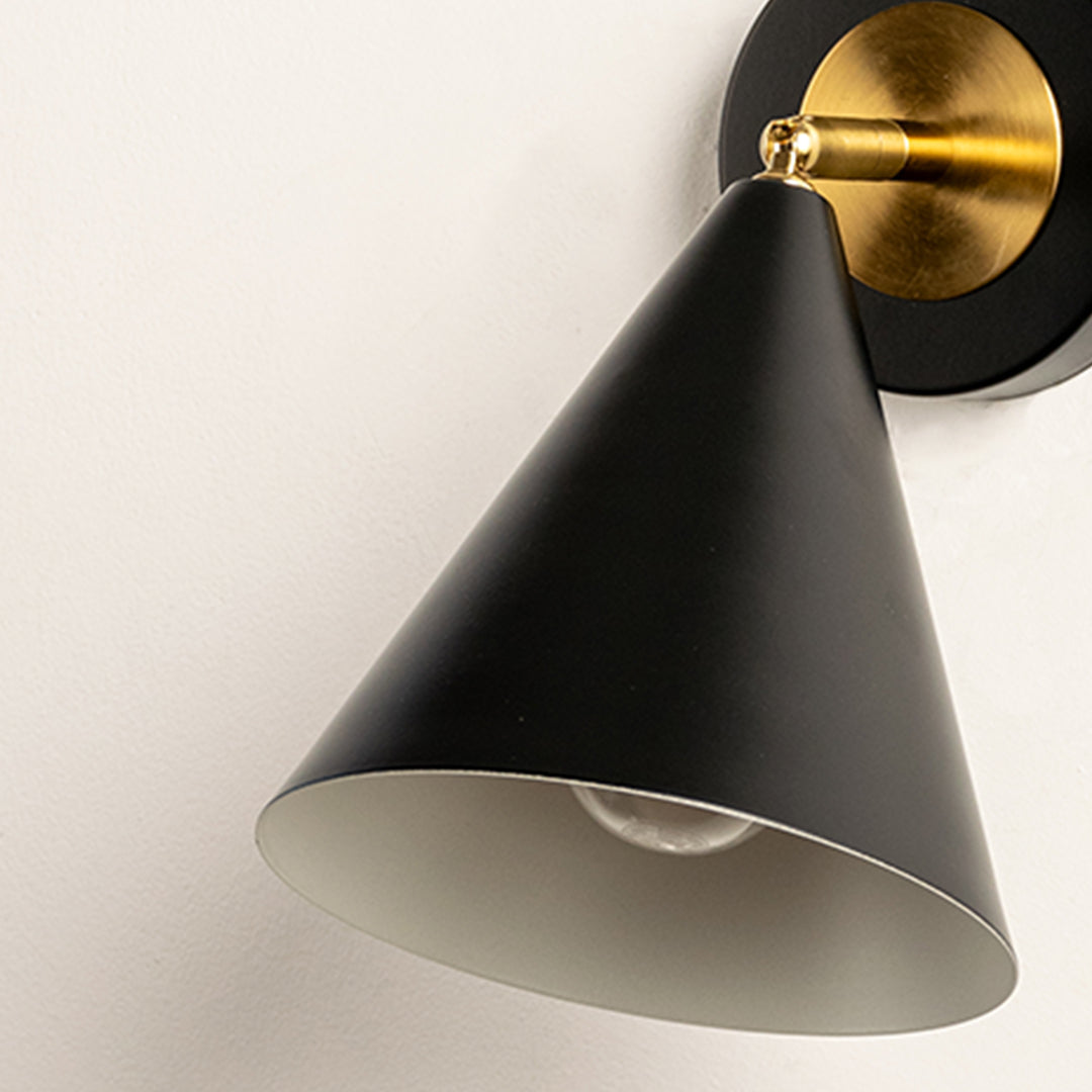 Closeup of black metal wall light with cone shade and gold mount showcasing smooth finish for modern interior decor styling.