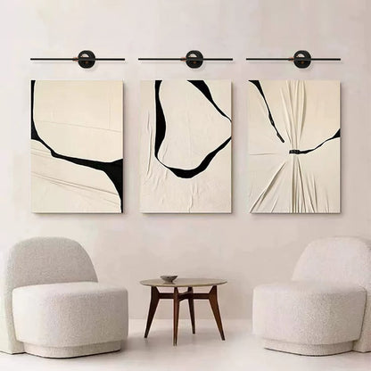Black and gold metal picture lights illuminating abstract artwork with focused lighting for contemporary living room decor.