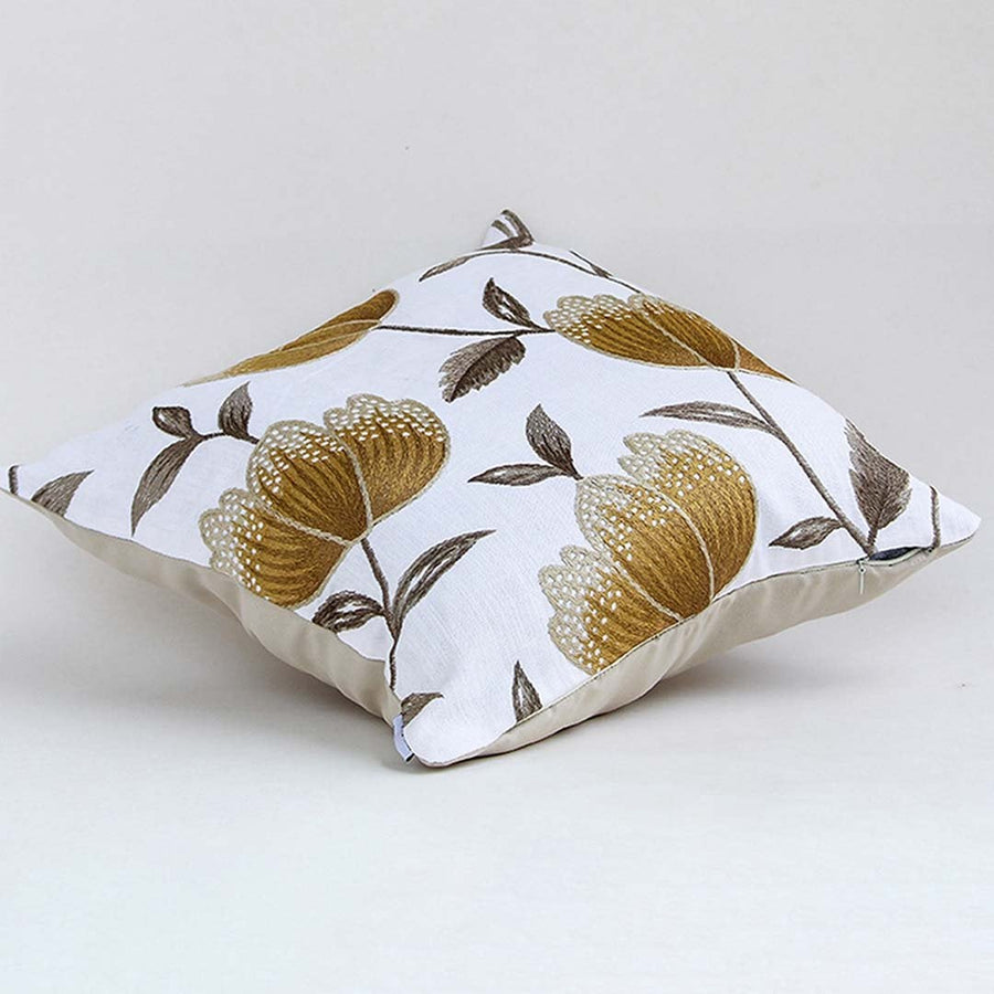 White cotton cushion cover with large golden botanical motifs shown at an angle adding a premium nature inspired décor accent with a soft breathable and skin friendly fabric.