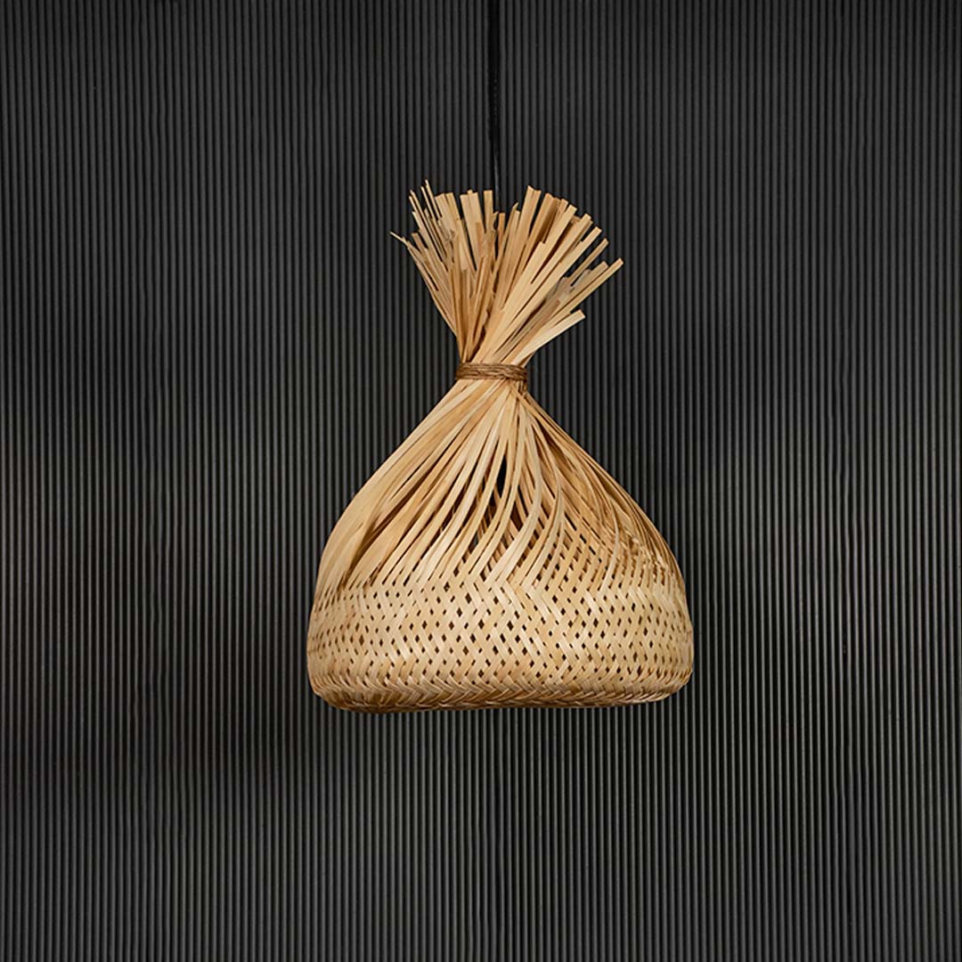 Woven rattan pendant light with tied top handcrafted shade shown off on black background for rustic home lighting.