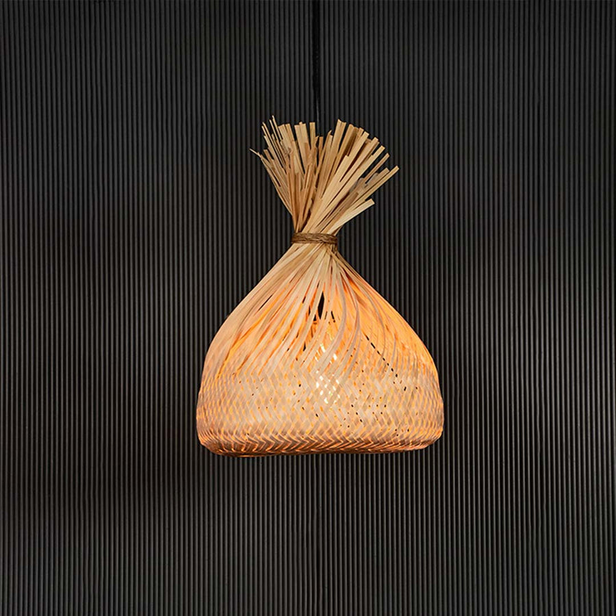 Handmade rattan pendant light with tied top woven shade displayed on black background for rustic home decor lighting.