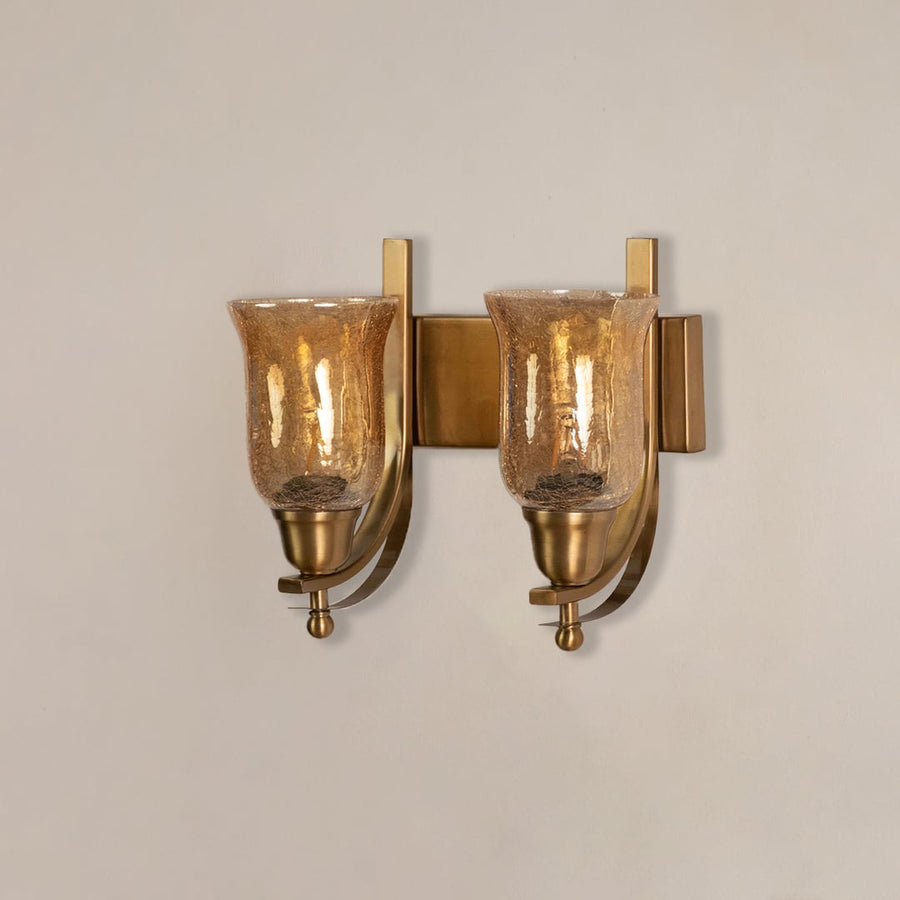 Contemporary brass double wall sconce with amber crackle glass shades switched off displayed on clean minimal white background.