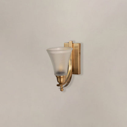 Modern brass wall lamp with frosted glass shade and curved bracket switched off displayed against dark black backdrop.