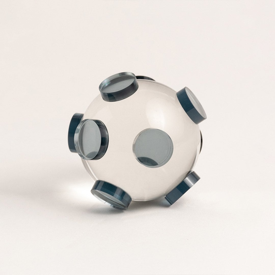Clear glass orb sculpture with grey circular accents displayed on white background for modern home styling.