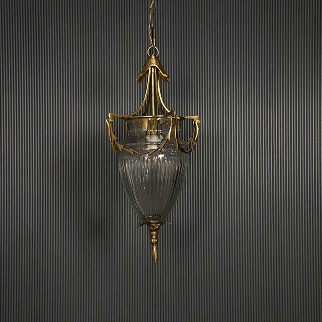Sleek antique brass hanging lamp turned off isolated on a pitch black background for a dramatic and high contrast presentation.