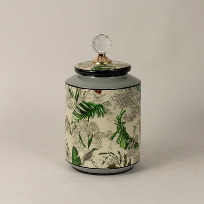 Side view of tropical bird jar highlighting cylindrical body vivid leaf artwork and shiny crystal top.