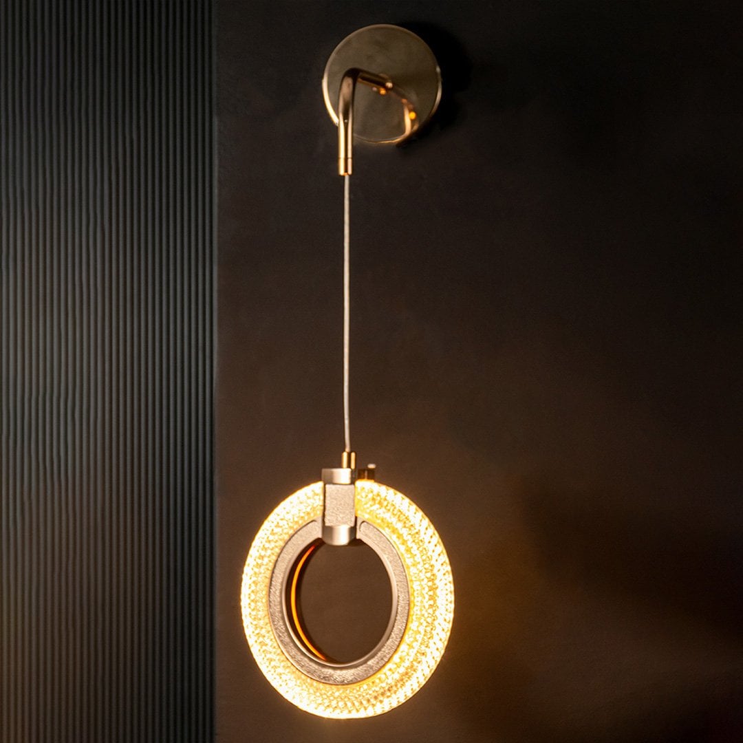 Modern gold crystal wall light turned on glowing against black wall creating premium decor look.