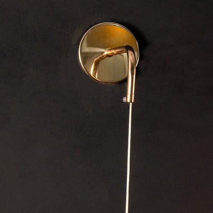 Closeup of gold metal wall light mount and curved arm highlighting smooth finish premium build and elegant lighting craftsmanship.